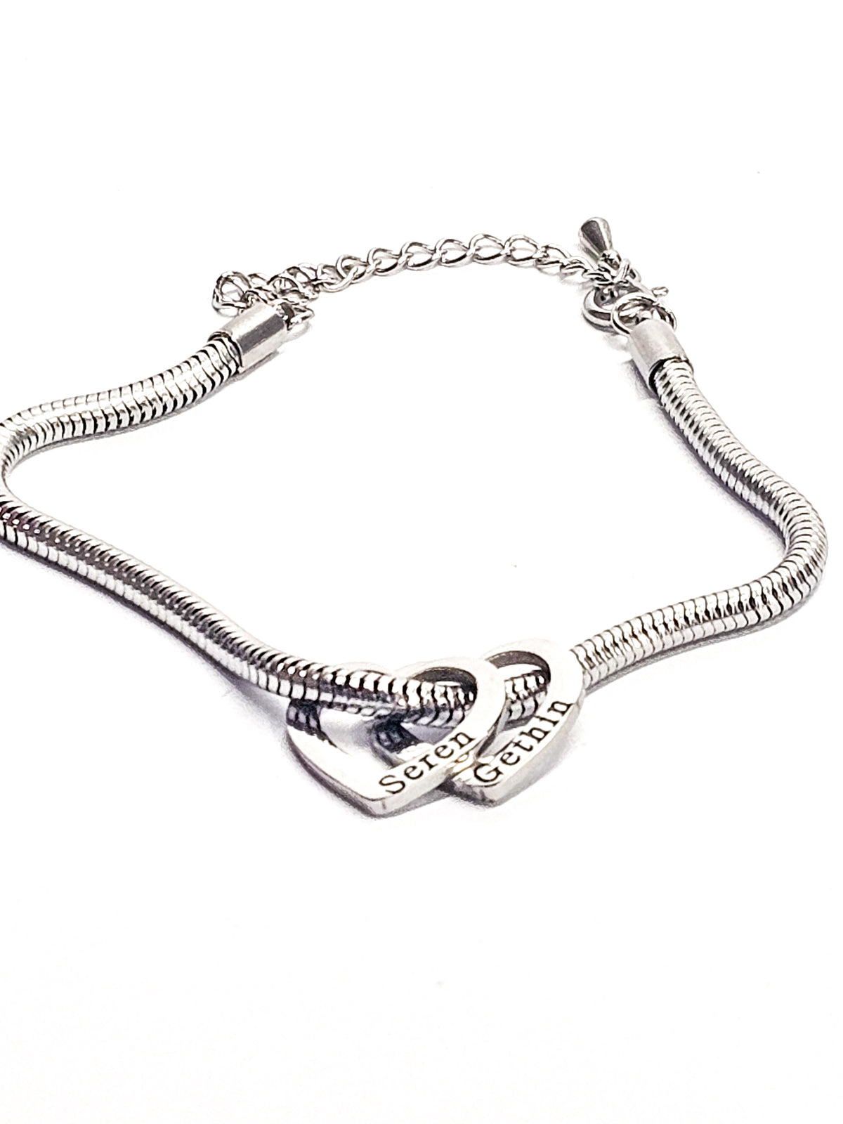 A silver-toned snake chain bracelet featuring two interlocking heart charms, one engraved with personalised engraving 